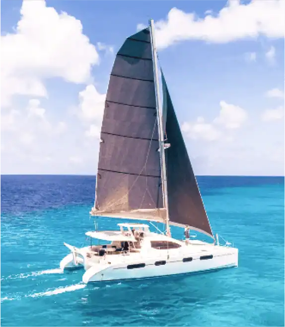 sail-with-destiny | Greenwood Beach Resort, Cat Island, Bahamas White catamaran sailing boat with a large dark sail on turquoise tropical water under a blue sky with scattered clouds